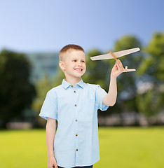 Image showing smiling little boy holding a wooden airplane model