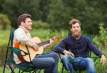 Image showing smiling tourists playing guitar in camping