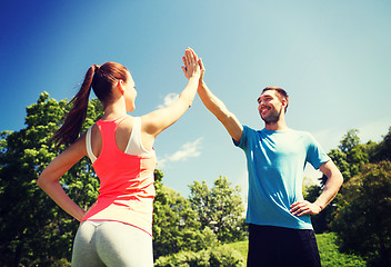 Image showing two smiling people making high five outdoors