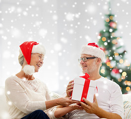 Image showing happy senior couple in santa hats with gift box