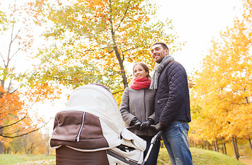 Image showing smiling couple with baby pram in autumn park