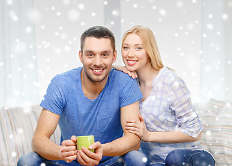 Image showing smiling couple with cup of tea or coffee at home