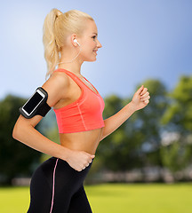 Image showing sporty woman running with smartphone and earphones