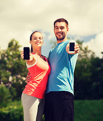 Image showing two smiling people with smartphones outdoors