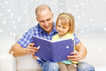 Image showing smiling father and daughter with book at home