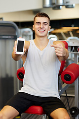 Image showing smiling young man with smartphone in gym