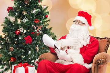 Image showing man in costume of santa claus with notepad