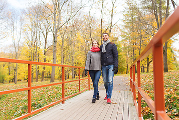 Image showing smiling couple hugging on bridge in autumn park