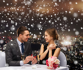 Image showing smiling couple with red gift box at restaurant