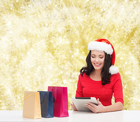 Image showing smiling woman in santa hat with bags and tablet pc