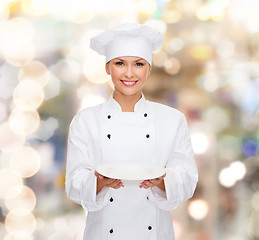 Image showing smiling female chef with empty plate