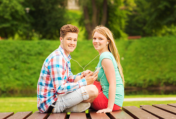 Image showing smiling couple with smartphone and earphones