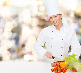 Image showing smiling female chef chopping vegetables