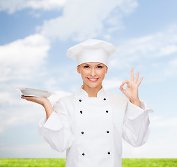 Image showing smiling female chef with plate showing ok sign