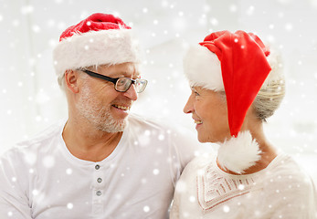 Image showing happy senior couple in santa helper hats at home