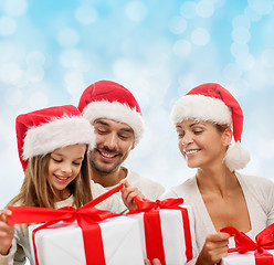 Image showing happy family in santa helper hats with gift boxes