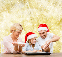 Image showing happy family in santa helper hats cooking