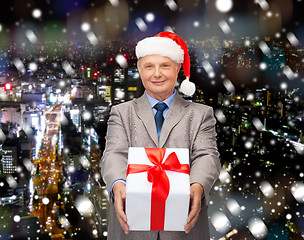 Image showing smiling man in suit and santa helper hat with gift