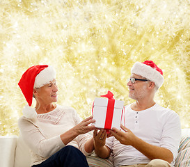 Image showing happy senior couple in santa hats with gift box