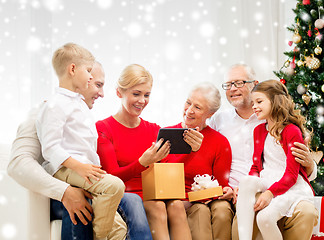 Image showing smiling family with tablet pc and gift box at home