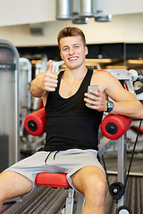 Image showing smiling young man with smartphone in gym