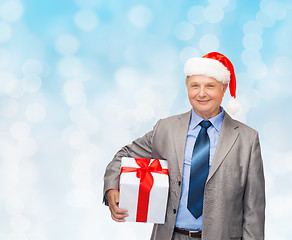 Image showing smiling man in suit and santa helper hat with gift