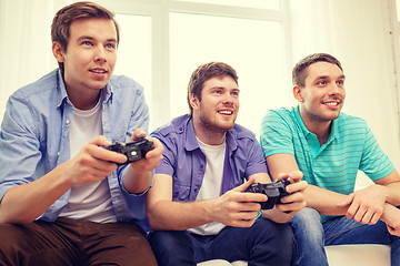 Image showing smiling friends playing video games at home