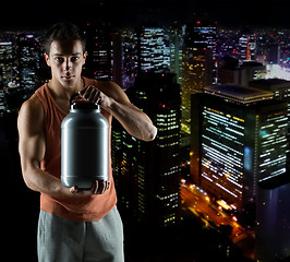 Image showing young male bodybuilder holding jar with protein