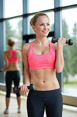 Image showing young sporty woman with dumbbells flexing biceps
