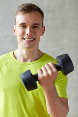 Image showing smiling man with dumbbell in gym