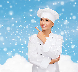 Image showing smiling female chef dreaming pointing finger up