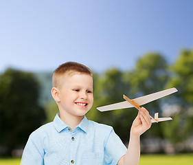 Image showing smiling little boy holding a wooden airplane model