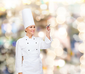 Image showing smiling female chef writing something on air