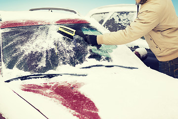 Image showing man cleaning snow from car windshield with brush
