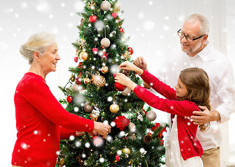 Image showing smiling family decorating christmas tree at home