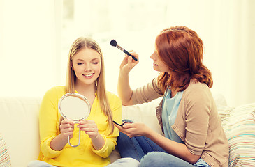 Image showing two smiling teenage girls applying make up at home