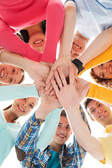 Image showing smiling teenagers with hands on top of each other