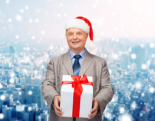 Image showing smiling man in suit and santa helper hat with gift