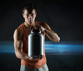 Image showing young male bodybuilder holding jar with protein