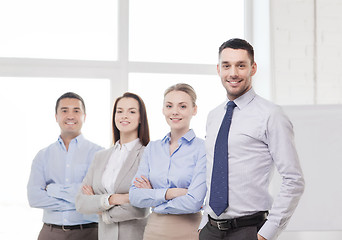 Image showing smiling businessman in office with team on back
