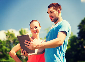 Image showing smiling couple with tablet pc outdoors