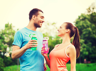 Image showing smiling couple with bottles of water outdoors