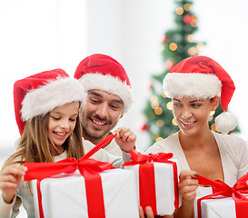 Image showing happy family in santa hats sitting with gift boxes