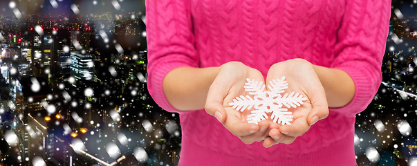 Image showing close up of woman in sweater holding snowflake