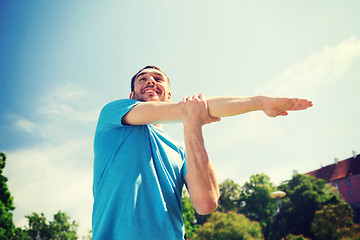 Image showing smiling man stretching outdoors