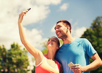 Image showing two smiling people with smartphones outdoors