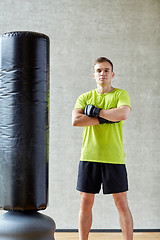 Image showing man with boxing gloves and punching bag in gym