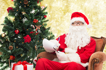 Image showing man in costume of santa claus with notepad