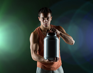 Image showing young male bodybuilder holding jar with protein