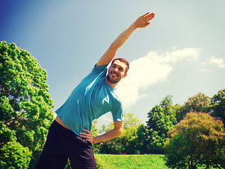 Image showing smiling man stretching outdoors